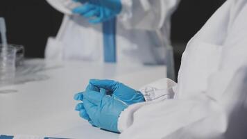 Two people in lab coats and gloves are holding something video