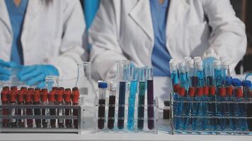 Two people in lab coats are working on a table with test tubes video