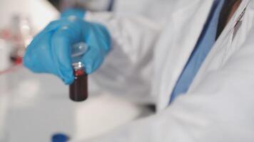 A person in a lab coat holding a red liquid video