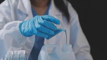 A woman in a lab coat is pouring liquid into a container video
