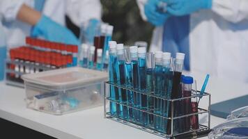 Two people in lab coats are working on a table with test tubes video