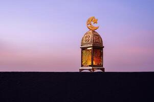 Golden lantern that have moon symbol on top with dusk sky background. photo