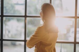 A woman standing in front of a window looking out photo