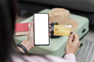 Woman hand hold blank smartphone with credit card and money on the table in coffee shop, online shopping concept. photo