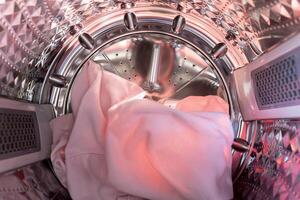 A view from inside a washing machine drum, showing colorful clothes, including knits photo
