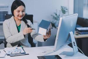 A woman is holding a house model in front of a computer photo