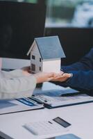 A real estate agent handing a house model to a client photo