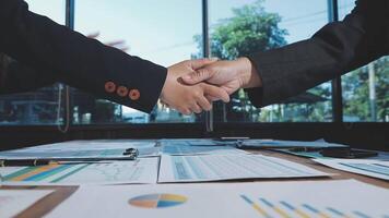 Two business people shaking hands over a table with papers video