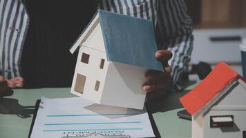 A real estate agent is holding a model of a house on a desk video