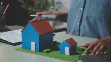 A person is working on a laptop and a model of a house video