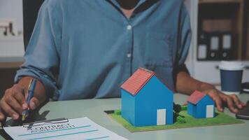 A man signing a contract with a house model video