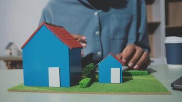 Man building model of house on table with laptop video