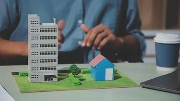 A man is working on a laptop with a model of a building video