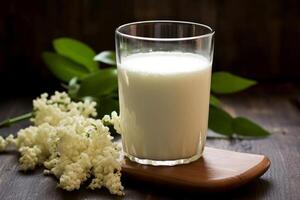 Glass of kefir or buttermilk in glass near flowers on the table. Fermented dairy product with probiotics. Useful drink for preserving your figure and diet. photo
