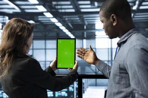 Team of engineers working in server farm, using chroma key tablet to analyze data. Employees working together in data center using isolated screen device, ensuring system integrity and security photo