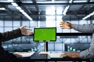 Technicians in data center using chroma key green screen tablet, refining server virtualization strategies. Server room colleagues using mockup device to configure cluster nodes photo