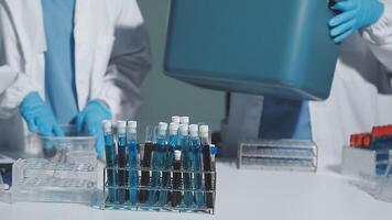 Two people in lab coats holding a container video