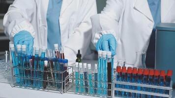 Two people in lab coats and gloves are working on a table video
