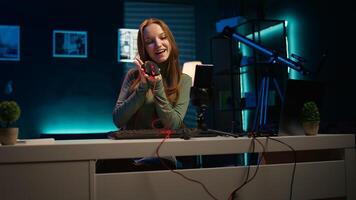 Gen Z girl presenting RGB lit mouse and keyboard while doing review in personal studio to see if price is justified. Young influencer showcasing neon lit computer peripheral features to fans, camera B photo