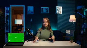 Tech expert presenting chroma key isolated screen laptop in entry level low budget price range. Gen Z influencer reviewing green screen notebook in front of internet subscribers, camera B photo