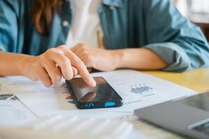 Close-up of a person using a smartphone to review financial documents and charts, highlighting modern business analysis. photo