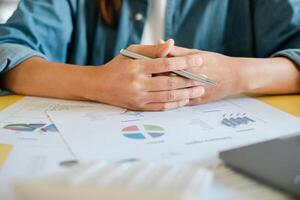 Close-up of hands holding a pen over financial documents with graphs and charts, representing business analysis and strategy. photo