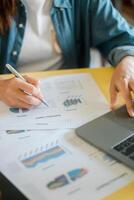 Close-up of a person reviewing financial documents with a laptop and pen, focusing on data analysis and business strategy. photo