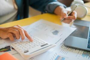 Close-up of hands using a calculator and reviewing financial charts, symbolizing business analysis and strategic planning. photo