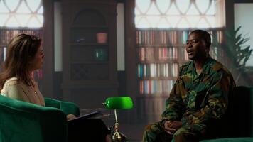 African american soldier looks distressed during a counseling session for trauma recovery, trying to open up and share his grief. PTSD support and mental health treatment for combatant. Camera B. photo