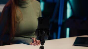 Focus on mobile phone used by influencer to film content for her online fans, talking about gen Z topics. Content creator records vlog for internet channel with cellphone on tripod, camera A close up photo