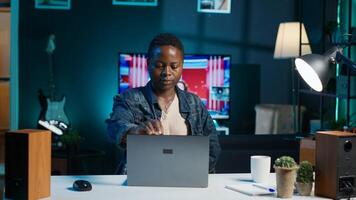Woman arriving in apartment office, sitting down at desk, opening laptop to begin doing tasks. Teleworker starting job shift at home, preparing notebook device, logging in online, camera A photo
