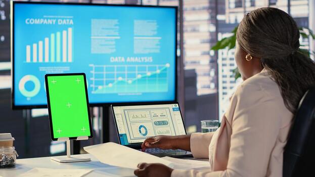 Female general manager working with isolated copy space on her tablet, working on financial planning with data analytics on laptop. Developing a strategy to increase funding for success. Camera A. photo