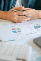 Close-up of hands holding a pen over financial documents with charts and graphs, indicating business analysis and strategy. photo