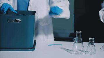 Two people in lab coats are working on a table video