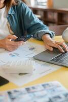 A person multitasking with a laptop and smartphone, analyzing data and charts in a modern office environment. photo