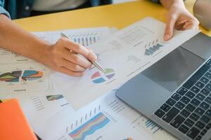 Close-up of hands reviewing financial charts and graphs on paper and laptop, showcasing business analysis and data interpretation. photo