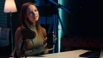 Tech specialist filming technology review of newly launched smartphone, presenting features to subscribers. Influencer advertising mobile phone to fans from home studio, camera A photo