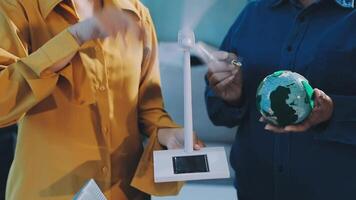 Two people holding a globe and a small computer video