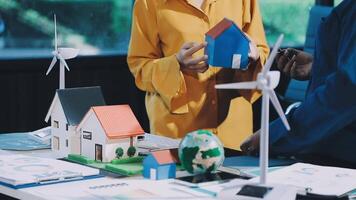A man and woman are looking at a model of a house and wind turbines video