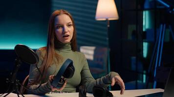 Gen Z influencer in home studio films headphones comparison for audience, recording with professional microphone to accurately capture sound, hosting technology internet show for fans, camera A photo
