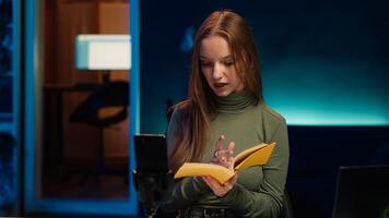 Young content creator films review of book, browsing through pages, presenting synopsis to audience. Internet star sponsored by publisher to show new novel release to readers, camera A photo