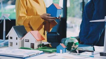 A woman is holding a model of a house with a wind turbine on it video