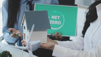 A woman holding a house model with a net zero sign video