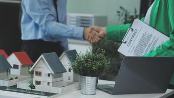 Two people shaking hands over a model of a house video