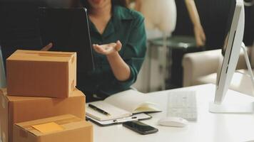 A woman is holding a tablet and looking at a stack of boxes video