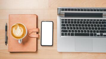 Office desk workspace with blank screen smart phone, laptop computer, notebook, pen and cup of coffee, Top view flat lay with copy space. photo
