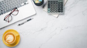 White office desk workspace with laptop computer, eyeglass, calculator, notebook, pen and cup of coffee, Top view flat lay with copy space. photo
