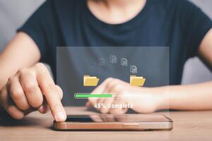 Transfer files data system relocation concept, Person hand using smart phone to waiting for transfer file process with loading bar icon on virtual screen. photo