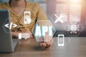 API, Application Programming Interface, Woman using laptop computer with VR screen API icon on office desk, Software development tool, modern technology, internet and networking concept. photo