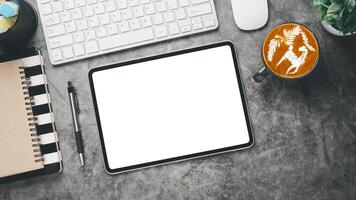 Office workplace with blank screen tablet, notebook, keyboard, mouse, pen and cup of coffee, Top view flat lay. photo